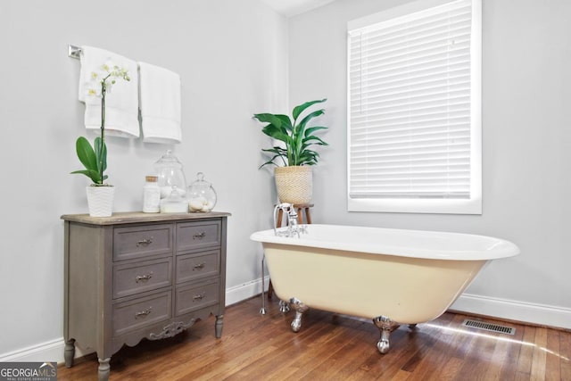 full bathroom featuring a soaking tub, baseboards, visible vents, and wood finished floors