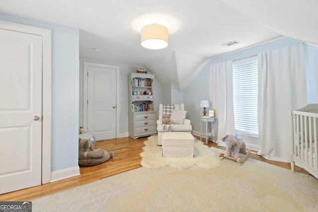 sitting room featuring lofted ceiling, baseboards, visible vents, and wood finished floors