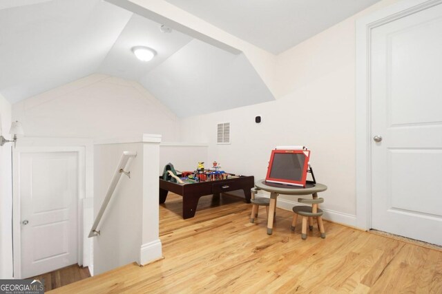 playroom featuring lofted ceiling, light wood-style floors, and visible vents