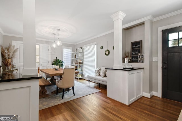 dining room with ornamental molding, dark wood-style flooring, decorative columns, and baseboards