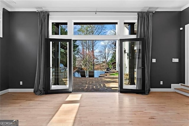 doorway to outside with ornamental molding, a wealth of natural light, and wood finished floors