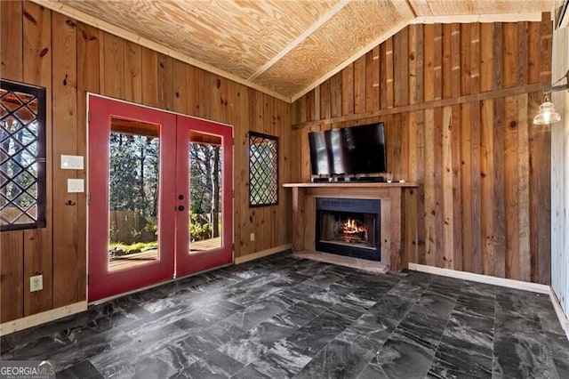 unfurnished living room featuring lofted ceiling, wooden walls, and french doors