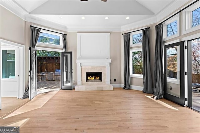 unfurnished living room with a healthy amount of sunlight, light wood-type flooring, and crown molding