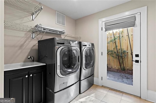 laundry area with light tile patterned flooring, a sink, visible vents, independent washer and dryer, and cabinet space