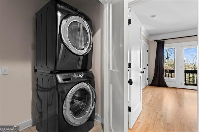 washroom with laundry area, baseboards, light wood-style floors, ornamental molding, and stacked washing maching and dryer