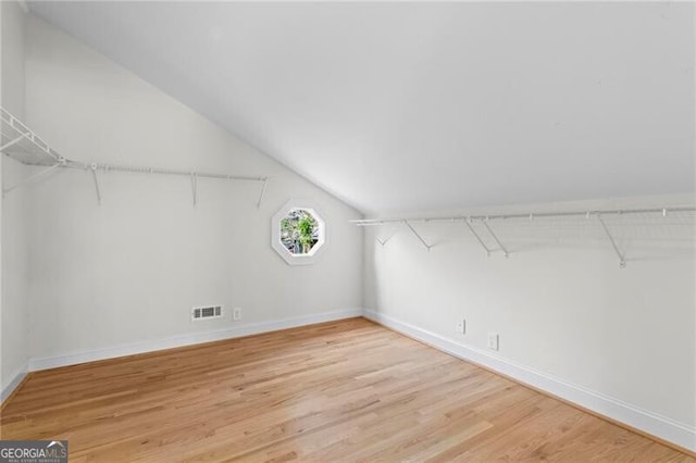 spacious closet featuring light wood-style floors, visible vents, and vaulted ceiling