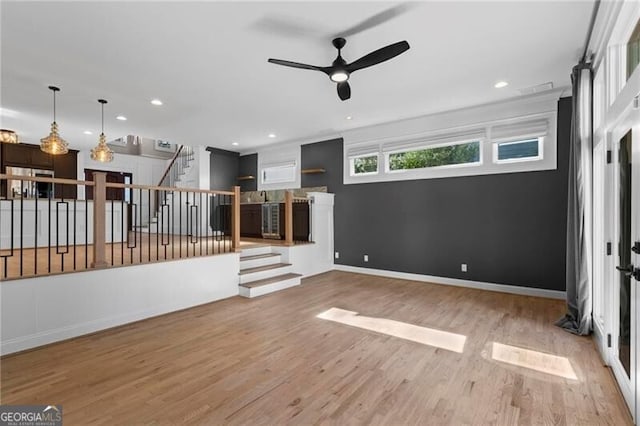 unfurnished living room with stairs, recessed lighting, wood finished floors, and baseboards