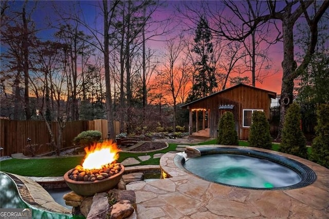 view of pool with fence, a fire pit, and an in ground hot tub