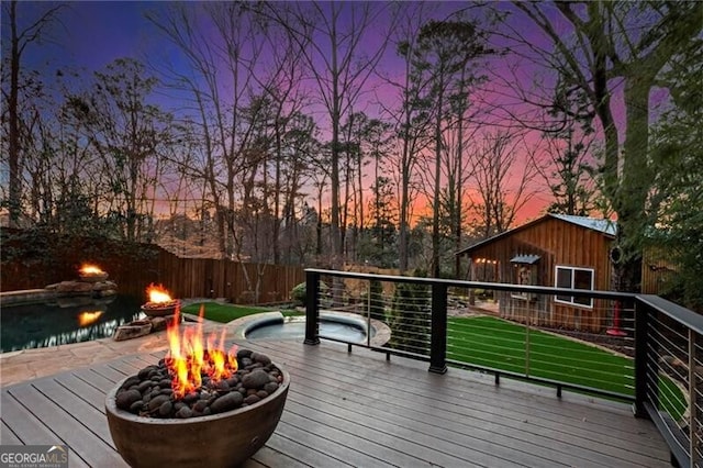 deck at dusk featuring fence and a fire pit