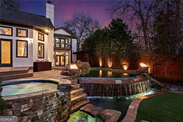 view of swimming pool featuring a fire pit, fence, a fenced in pool, and an in ground hot tub