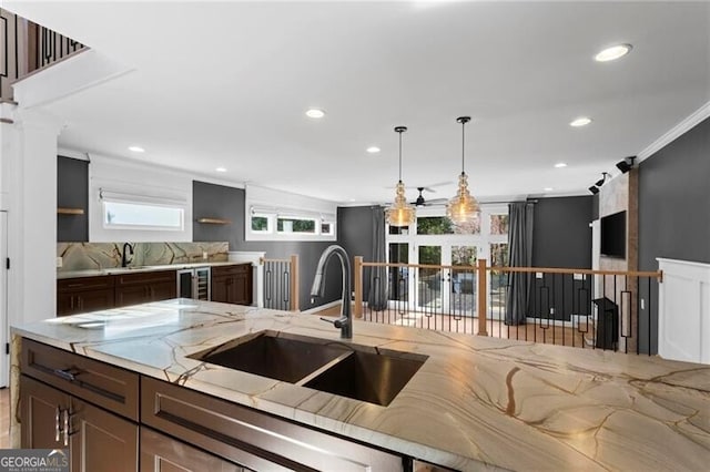 kitchen with light stone counters, a barn door, ornamental molding, a sink, and beverage cooler