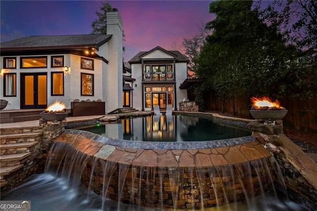 back of house at dusk featuring an outdoor fire pit and a chimney