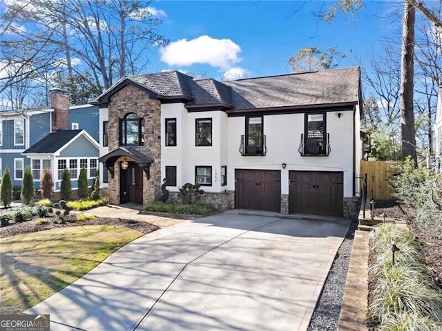 view of front of home with stucco siding, concrete driveway, an attached garage, fence, and stone siding