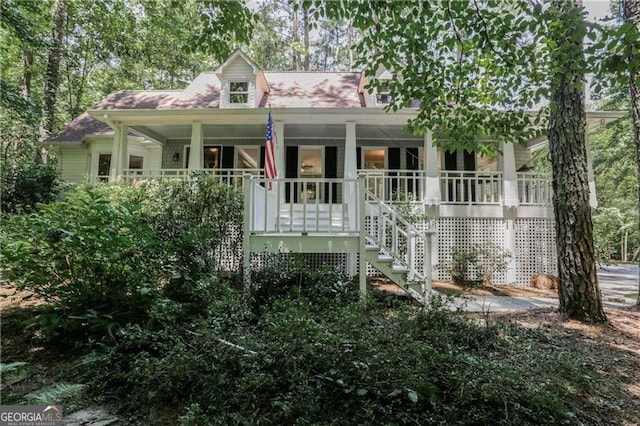 cape cod-style house featuring covered porch and stairway