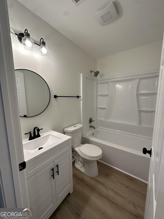 full bath featuring toilet, shower / bathtub combination, wood finished floors, and vanity