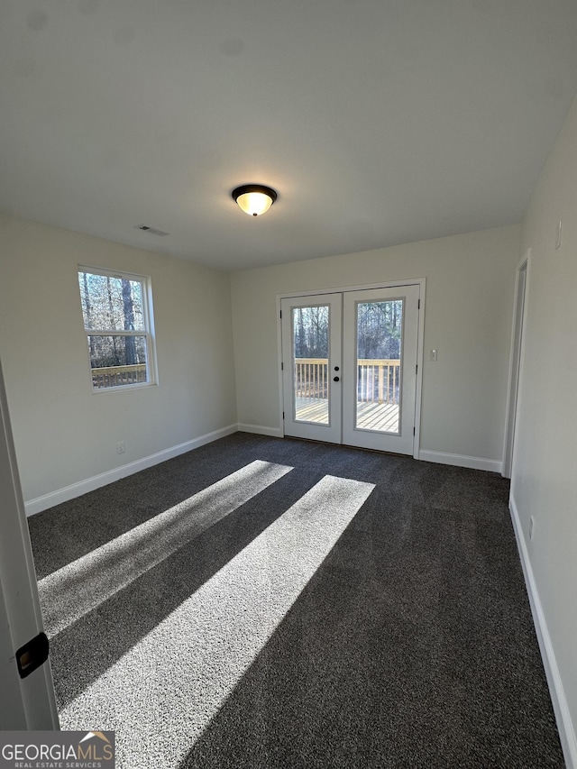 unfurnished room featuring baseboards, visible vents, dark carpet, and french doors