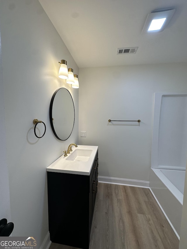 full bath featuring baseboards, visible vents, wood finished floors, and vanity