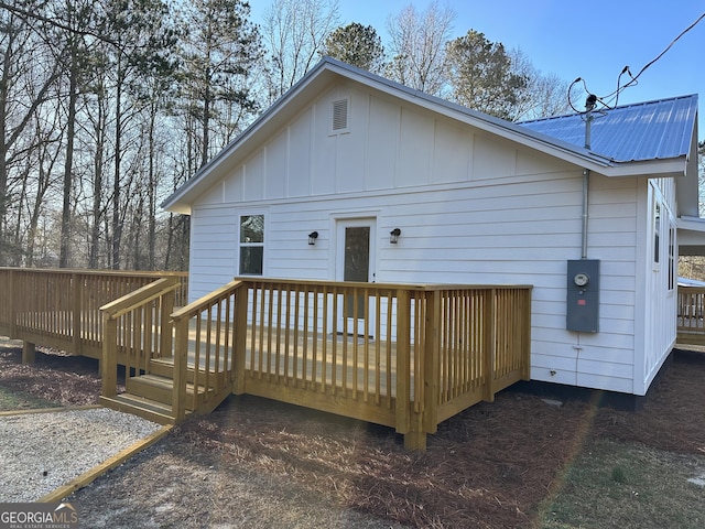 back of house with a deck, metal roof, and board and batten siding