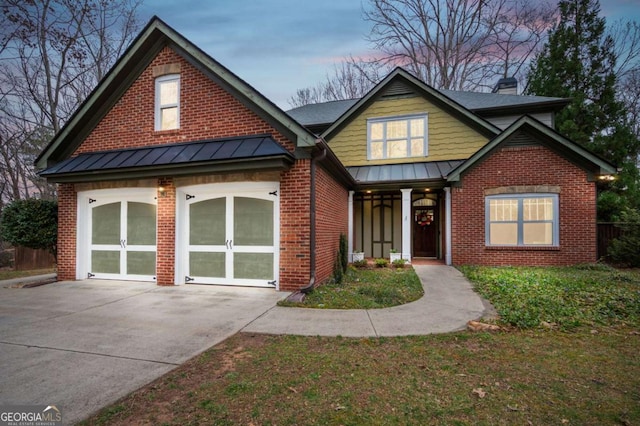 view of front of property featuring brick siding, a chimney, concrete driveway, a standing seam roof, and a garage