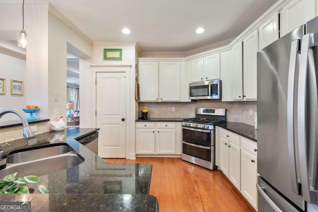 kitchen featuring light wood finished floors, backsplash, stainless steel appliances, and a sink