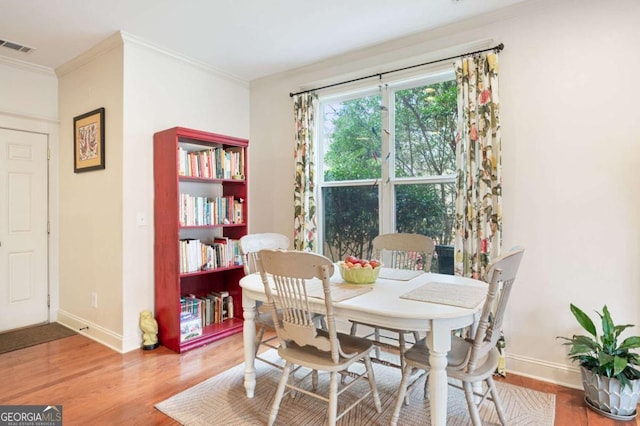 dining area featuring visible vents, ornamental molding, and wood finished floors