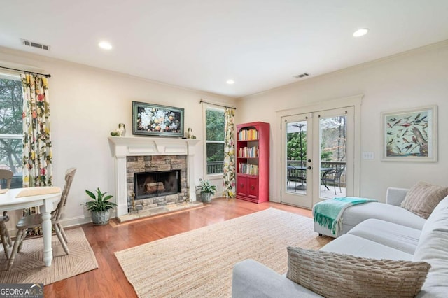 living room with french doors, visible vents, a fireplace, and wood finished floors