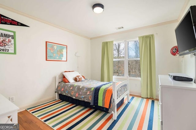 bedroom with ornamental molding, visible vents, light wood-style floors, and baseboards