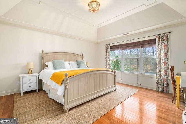 bedroom with visible vents, baseboards, and hardwood / wood-style flooring