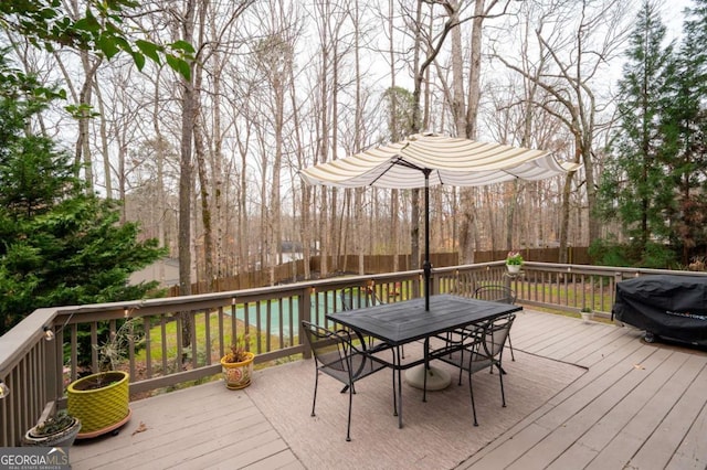 wooden deck with outdoor dining space, fence, and area for grilling