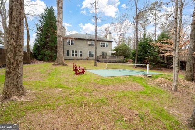 back of property with a yard, a chimney, and fence