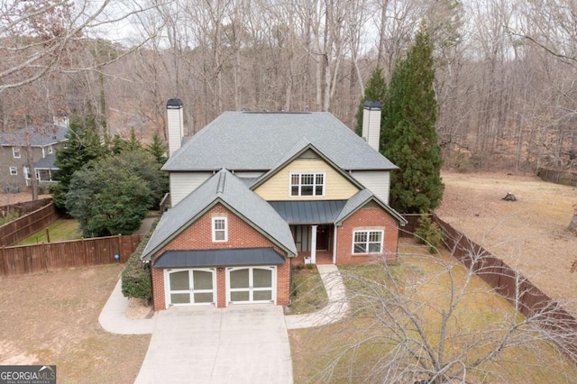 view of front of property with brick siding, a chimney, concrete driveway, fence, and a garage