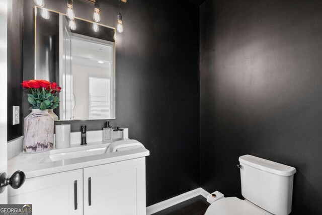 bathroom with baseboards, vanity, and toilet