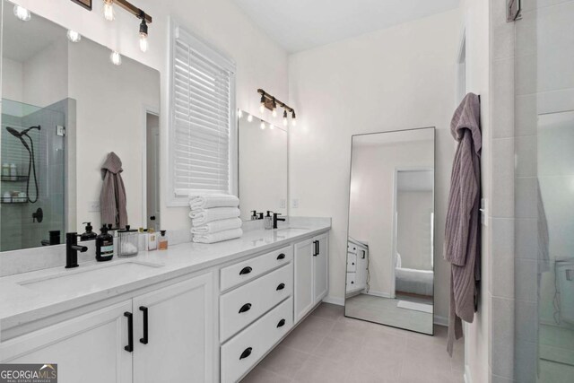 full bath with a stall shower, tile patterned flooring, a sink, and double vanity