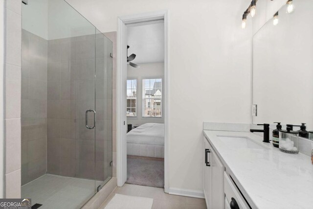 ensuite bathroom with tile patterned flooring, connected bathroom, vanity, a ceiling fan, and a stall shower