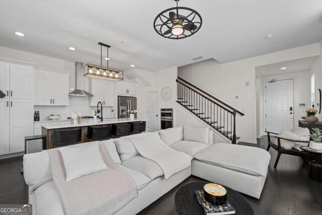 living area with dark wood-style floors, recessed lighting, visible vents, and stairs