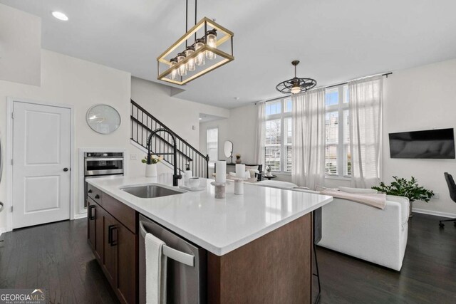 kitchen featuring hanging light fixtures, appliances with stainless steel finishes, open floor plan, and dark wood finished floors