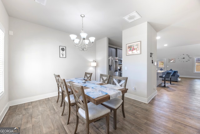 dining room with visible vents, a notable chandelier, baseboards, and wood finished floors