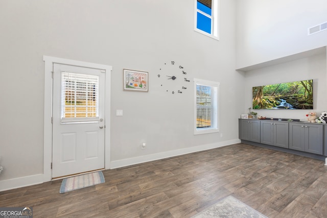 entrance foyer with a high ceiling, wood finished floors, visible vents, and baseboards