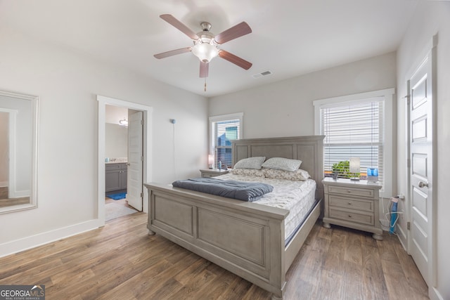 bedroom with visible vents, ensuite bathroom, ceiling fan, light wood-type flooring, and baseboards