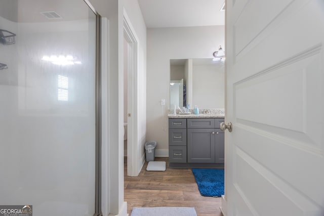 full bathroom featuring a stall shower, visible vents, wood finished floors, and vanity