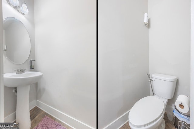 bathroom featuring toilet, a sink, baseboards, and wood finished floors