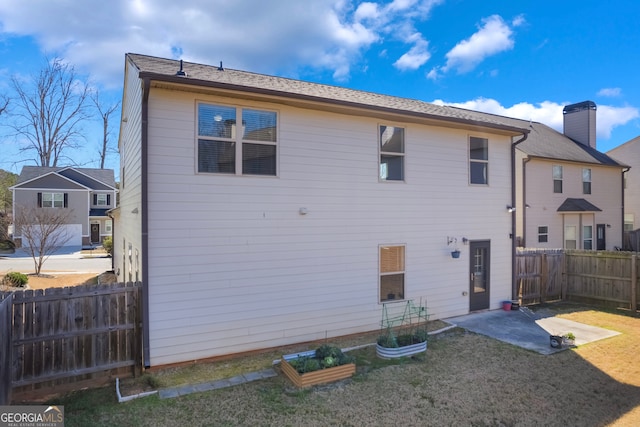 back of house with a yard, a patio area, fence, and a garden