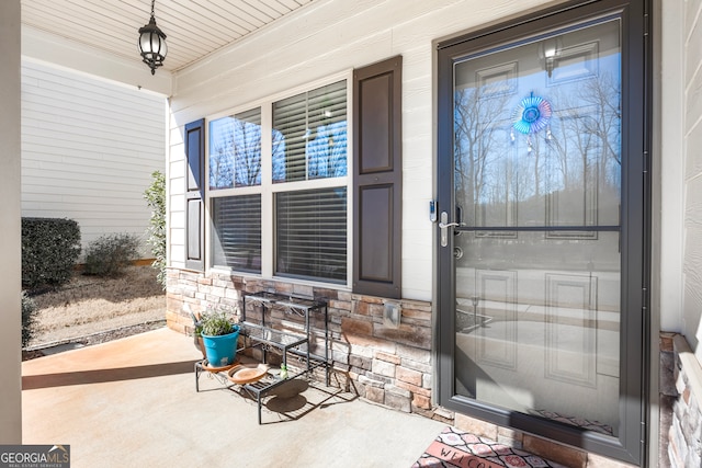 view of exterior entry featuring covered porch and stone siding