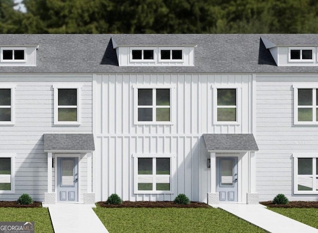 view of front of property featuring roof with shingles, a front lawn, and board and batten siding