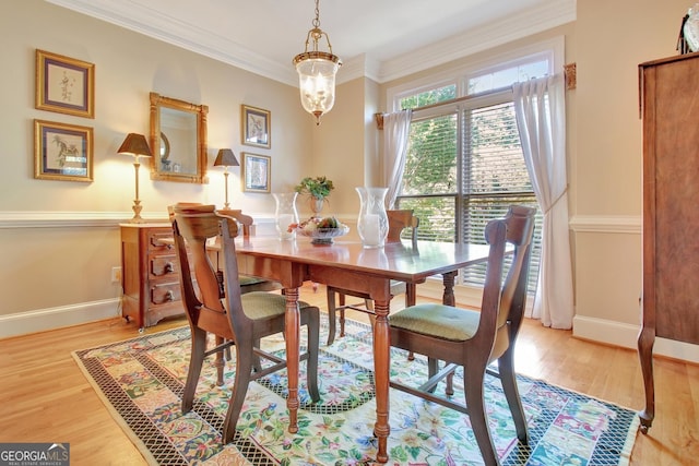 dining area featuring a chandelier, light wood finished floors, baseboards, and crown molding