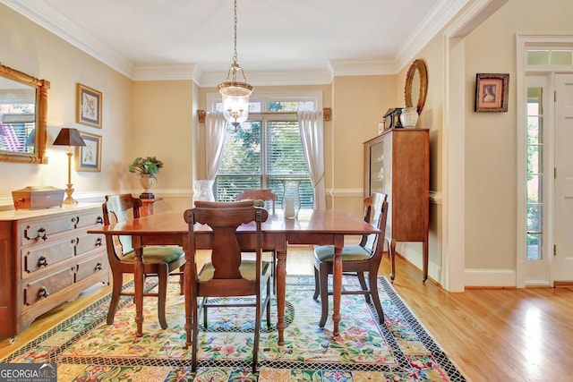 dining area featuring baseboards, ornamental molding, an inviting chandelier, and light wood-style floors