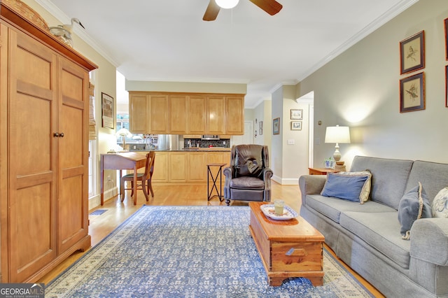 living room with ornamental molding, light wood-type flooring, baseboards, and a ceiling fan