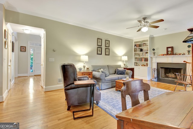 living room with light wood-style floors, baseboards, ornamental molding, and a fireplace with flush hearth