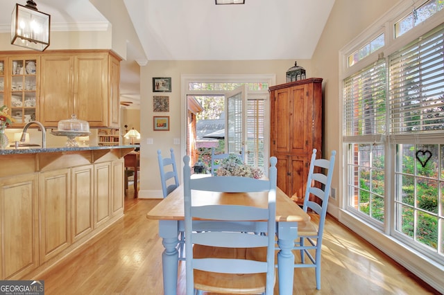 dining room featuring light wood-style flooring, baseboards, and vaulted ceiling