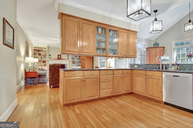 kitchen with dishwasher, dark stone countertops, a sink, and crown molding